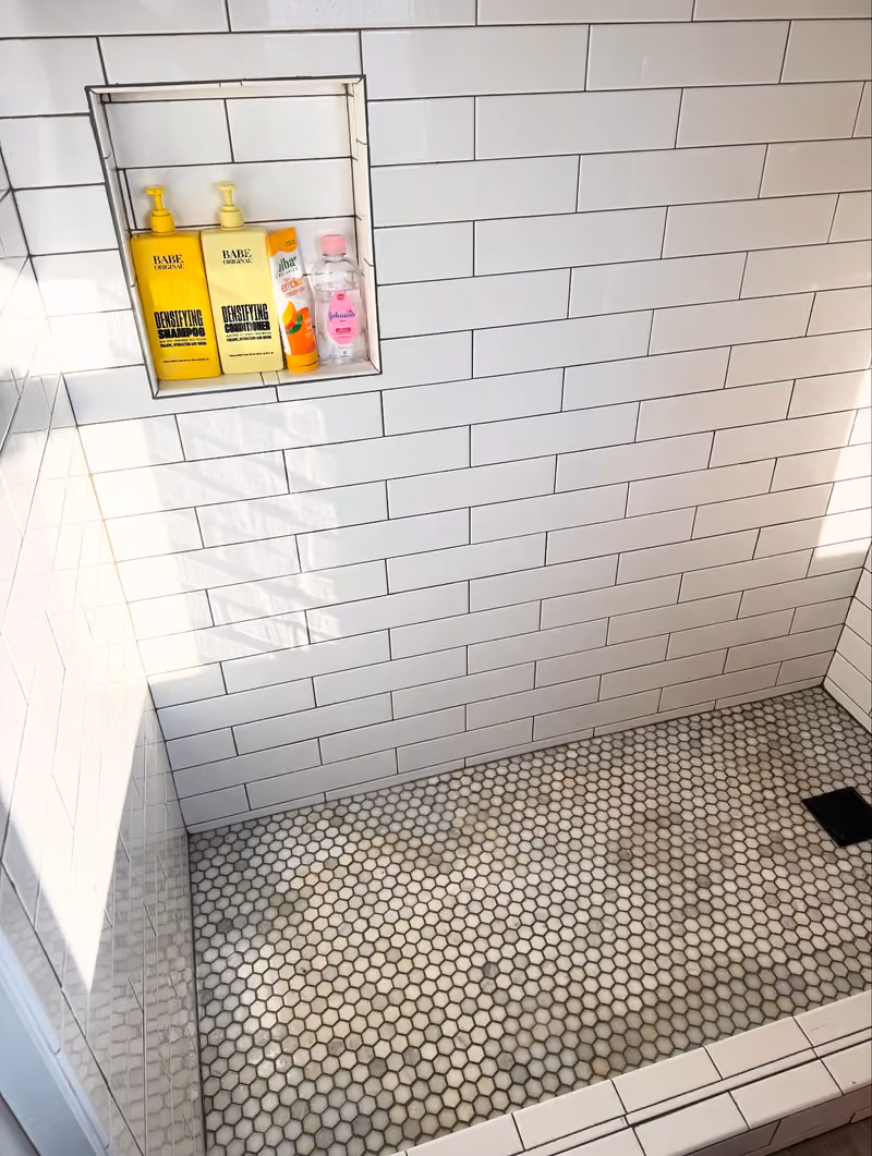 After: the same shower with bright white tile and clean grout